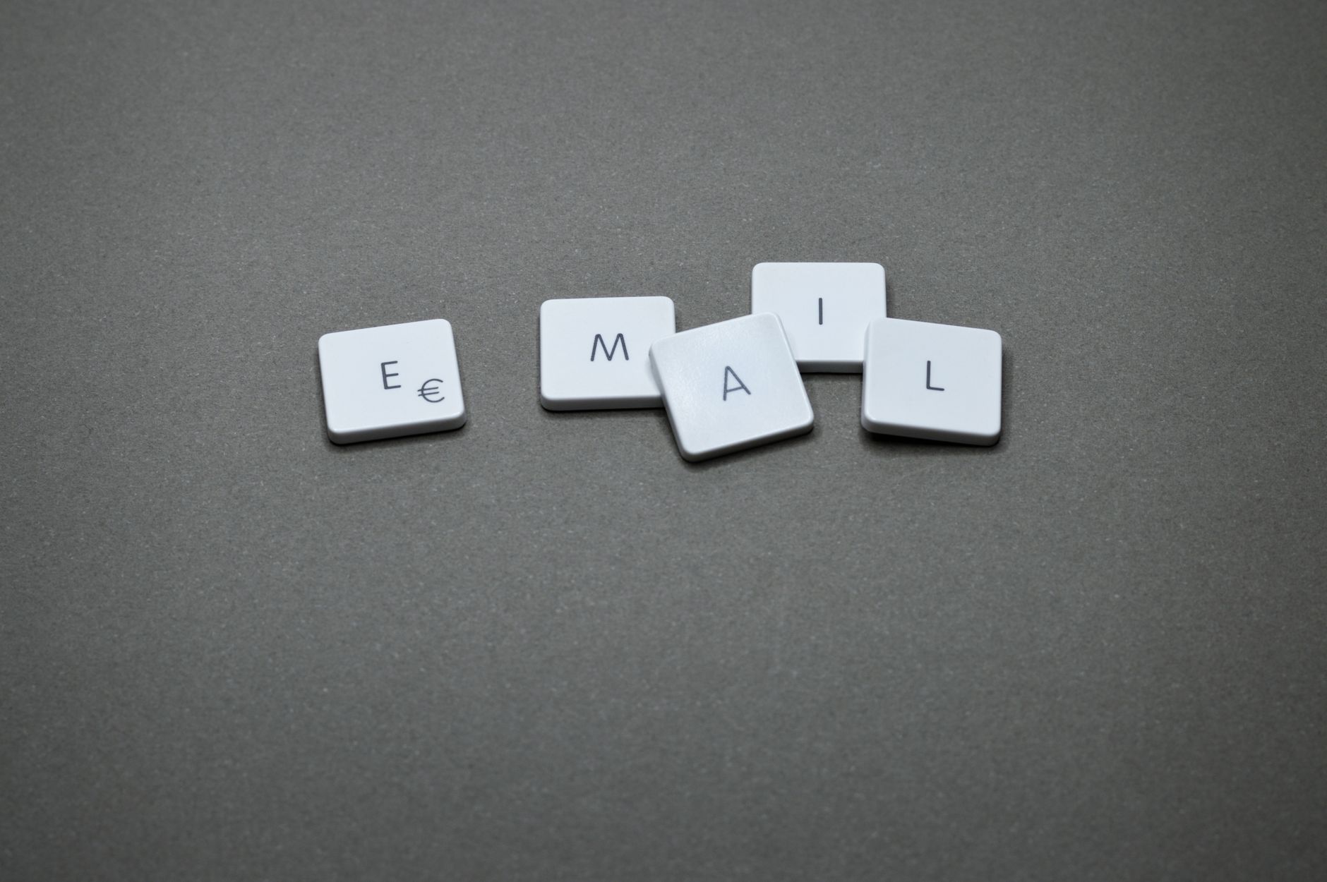 fenomeno newsletter — Close-up of the word 'email' formed with letter tiles on a gray surface.