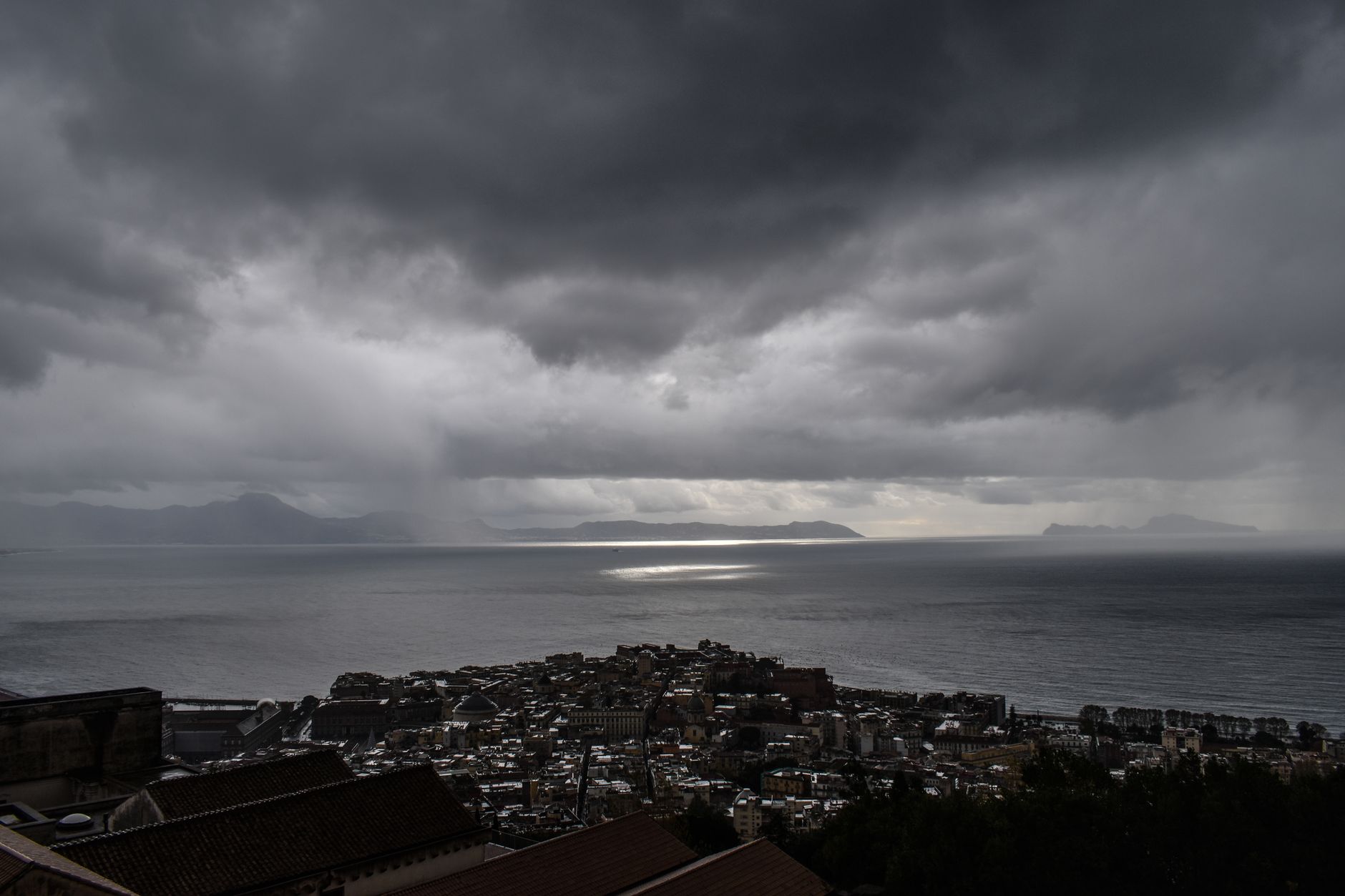 Moody clouds hover over the Napoli coastline, creating a dramatic seascape view.
