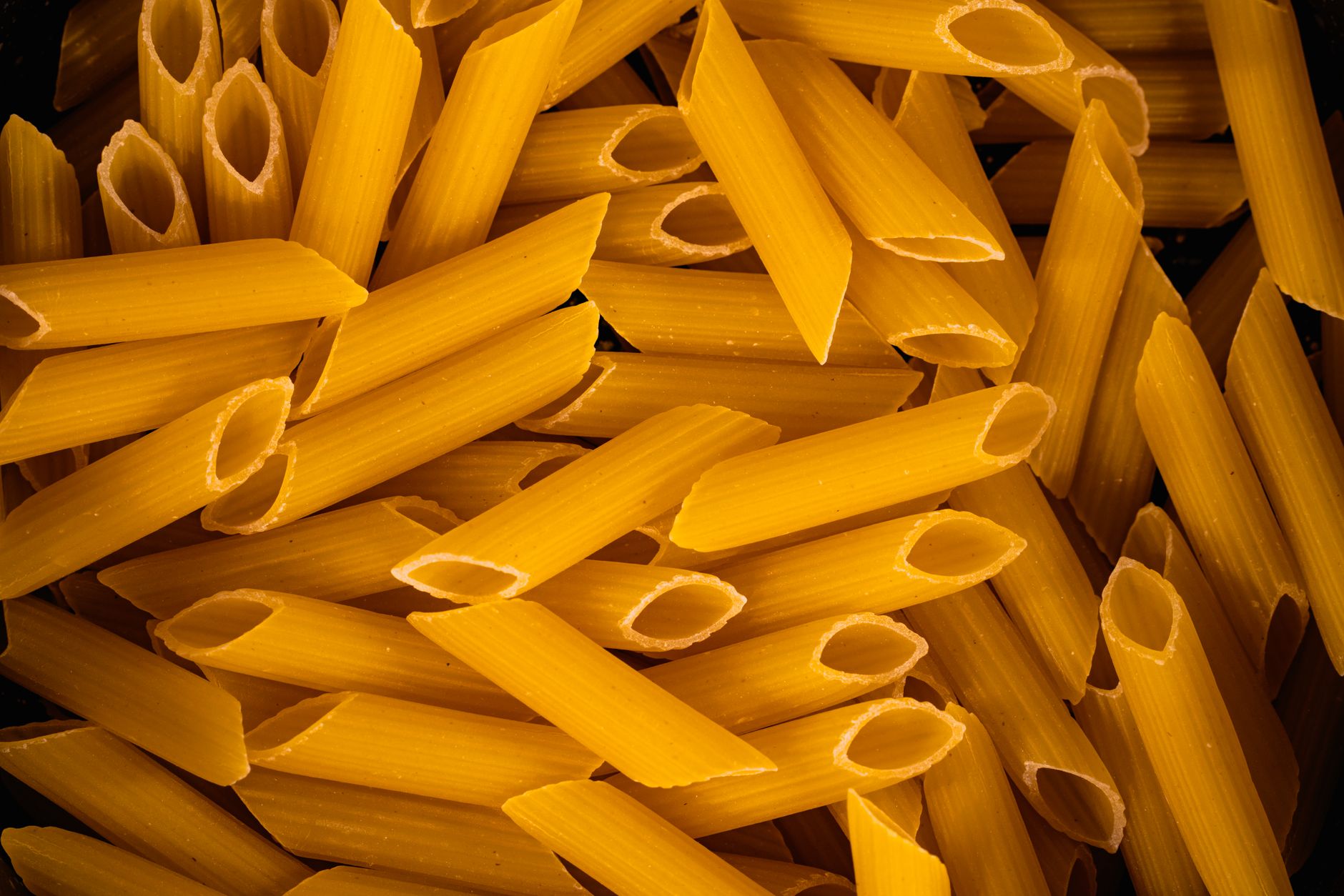 High-definition close-up of uncooked penne pasta, showcasing texture and detail.