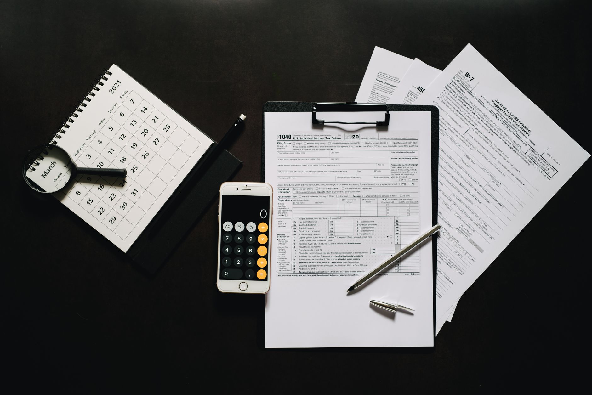 fiscal drag — Flat lay of financial tools for tax preparation including forms, calculator, and calendar.