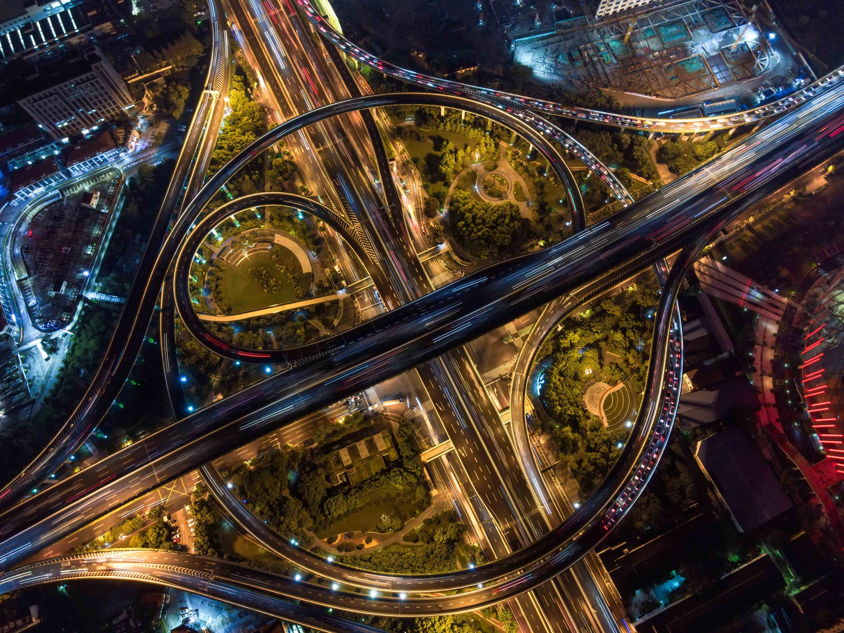Stunning aerial view of intricate city highways and roundabouts illuminated at night.