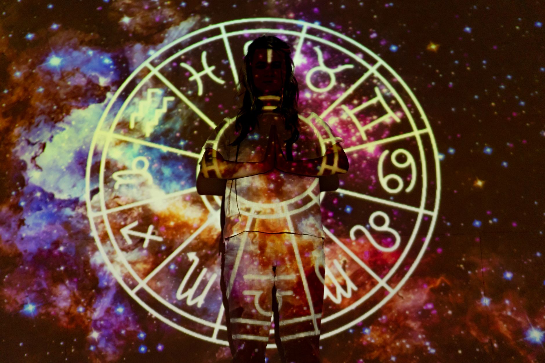 oroscopo del 2 ottobre — Silhouette of a person with celestial astrology symbols against a cosmic background.